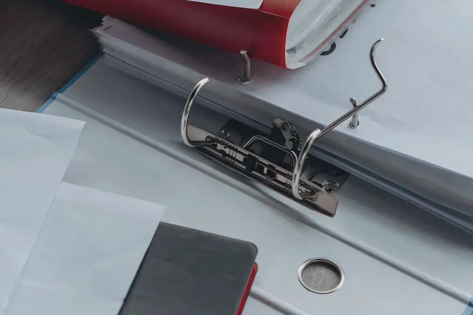 An open lever-arch file holding a thick stack of papers.